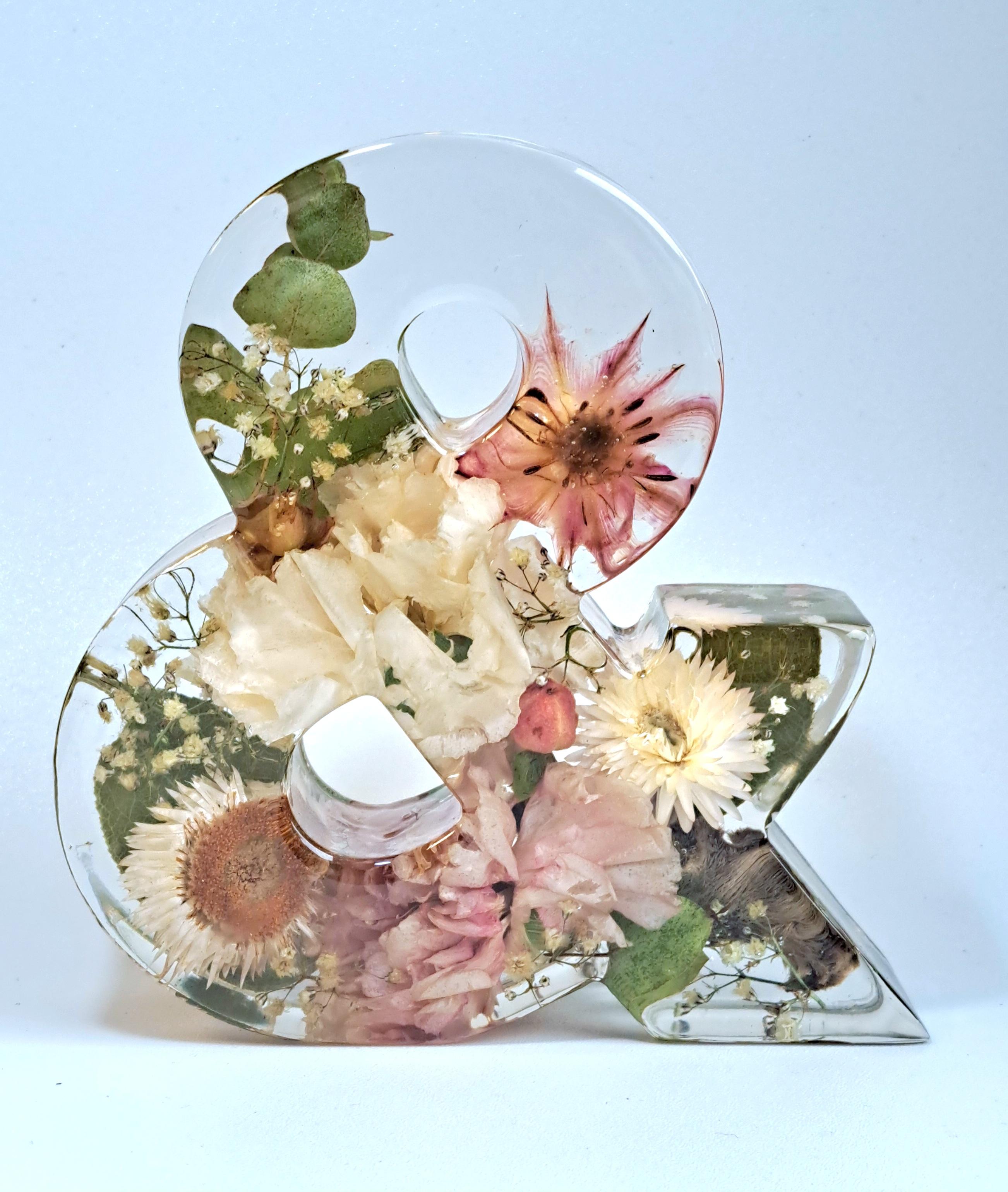 Eingearbeitet sind rosa-weiße Blumen mit grünem Blattwerk im Hintergrund.